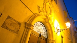 An ornate entrance with a decorative iron gate, a sign with text, and a wall-mounted light fixture.
