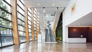 En rummelig lobby med en central rulletrappe, store vinduer og en receptionsdisk.