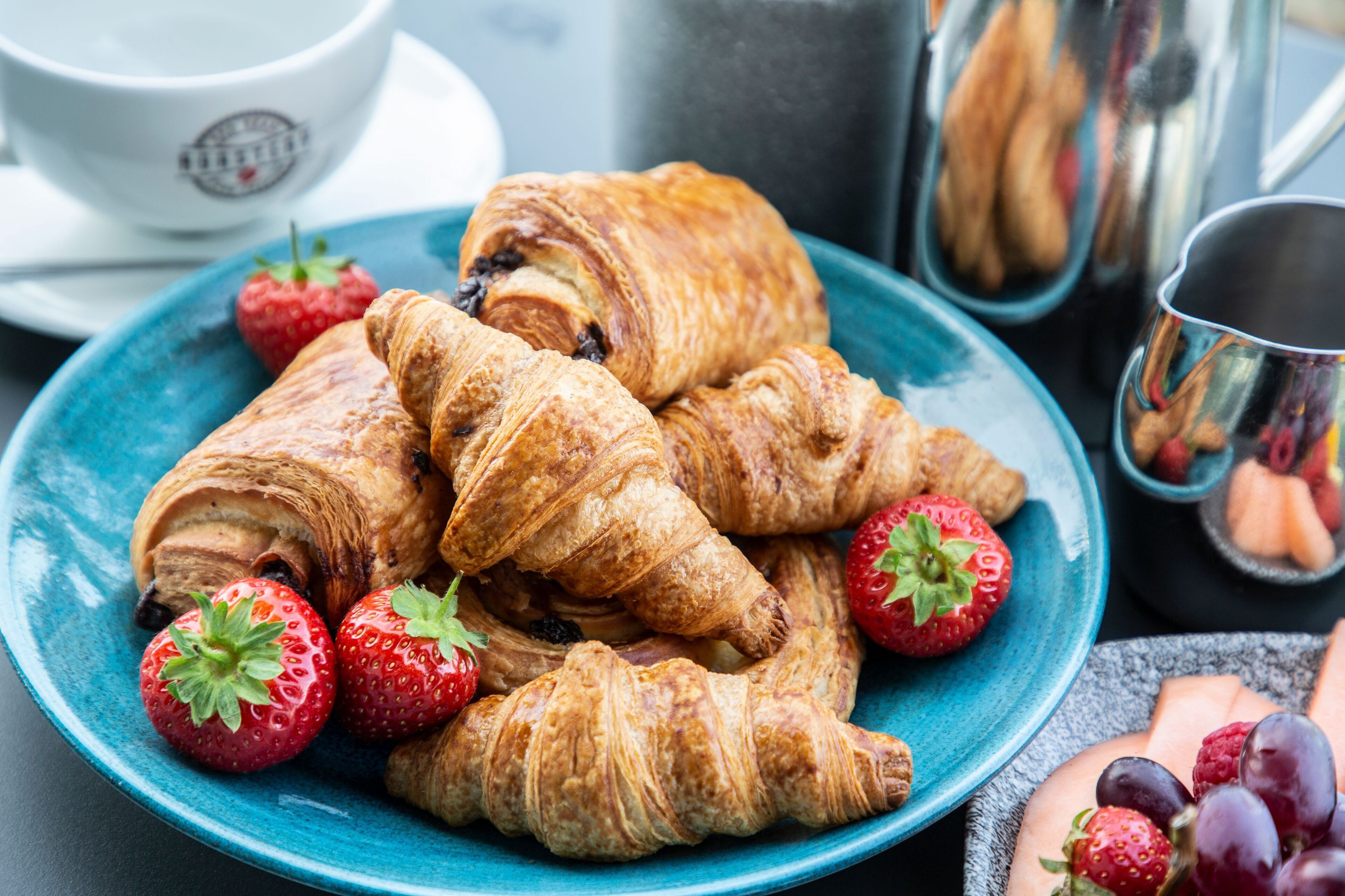 A plate of croissants with strawberries on a blue plate.