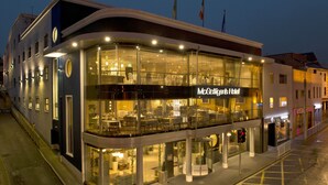 Een modern hotel met een glazen gevel, terras en een opvallend bord.