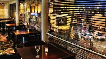 En restaurant med borde og stole, udsigt til gaden og et gelænder med vandrette lister.