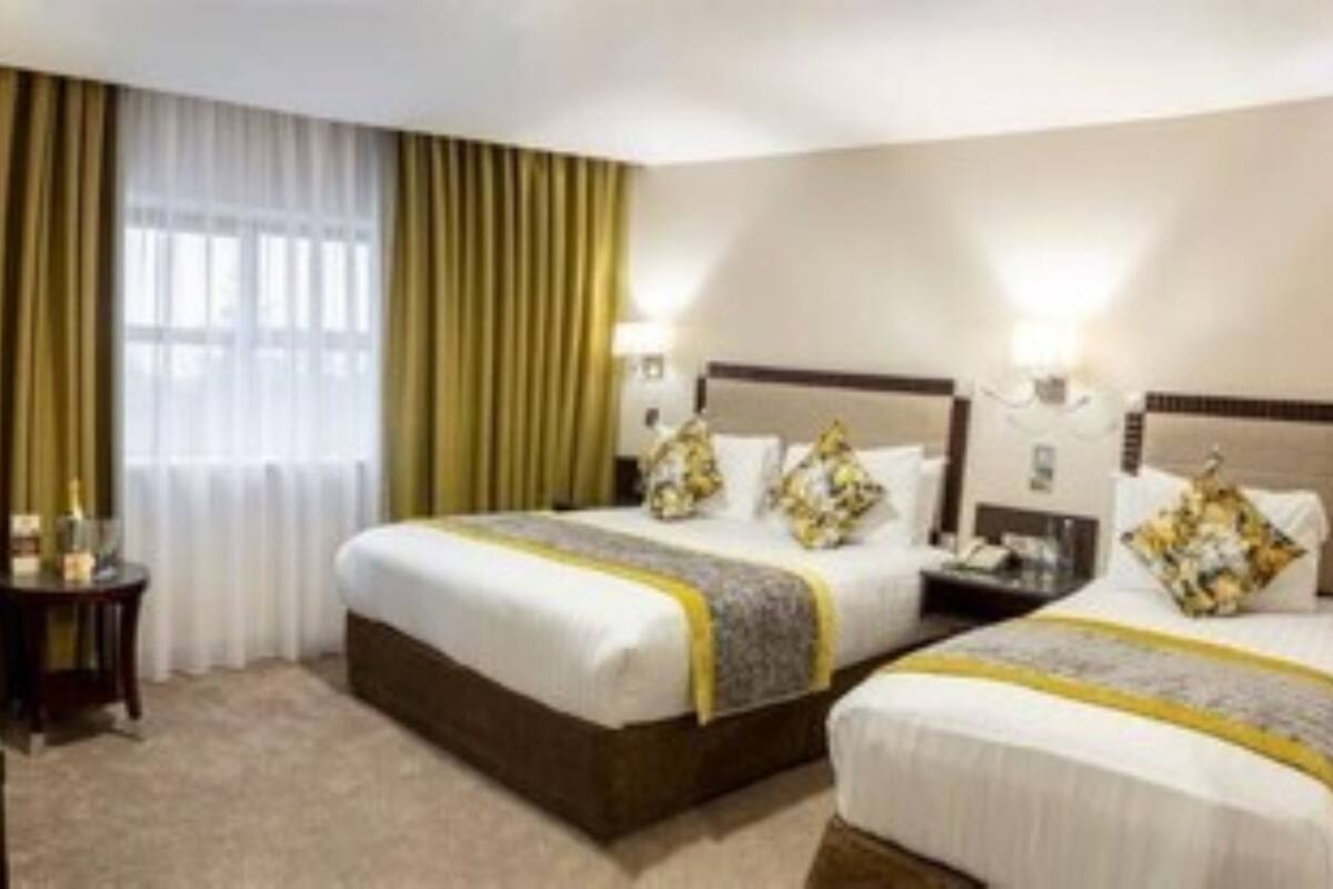 Ein Hotelzimmer mit zwei Betten, einem Schreibtisch, einem Stuhl und einem Vorhangfenster.