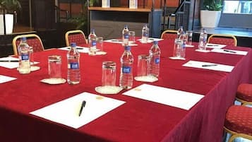 A conference room with tables set for a meeting, equipped with water bottles and notepads.