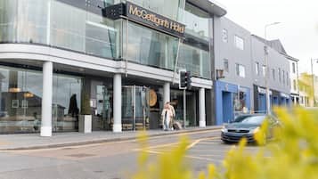 Un hotel moderno con fachada de vidrio, un cartel que dice 'McGettigan's Hotel' y un paso de peatones.