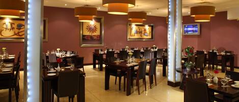 A restaurant with multiple dining tables, chairs, and pendant lighting.