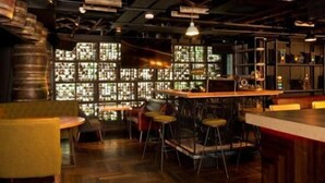 Een bar met krukken, een toog en een groot raam met glas-in-lood.