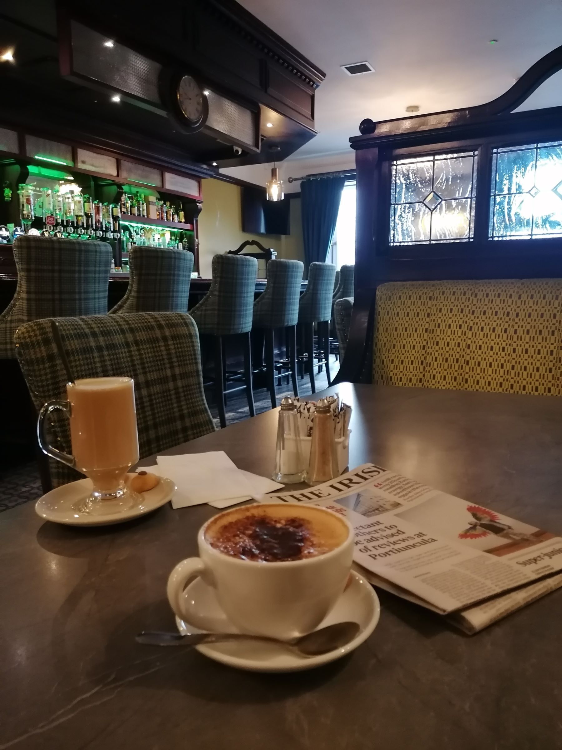 A table with a coffee and a dessert, bar area with chairs, and a window with a view.