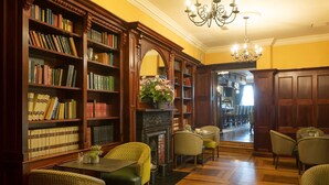 A library with wooden bookshelves, a fireplace, and comfortable seating areas. - Cahir House Hotel (Cahir)