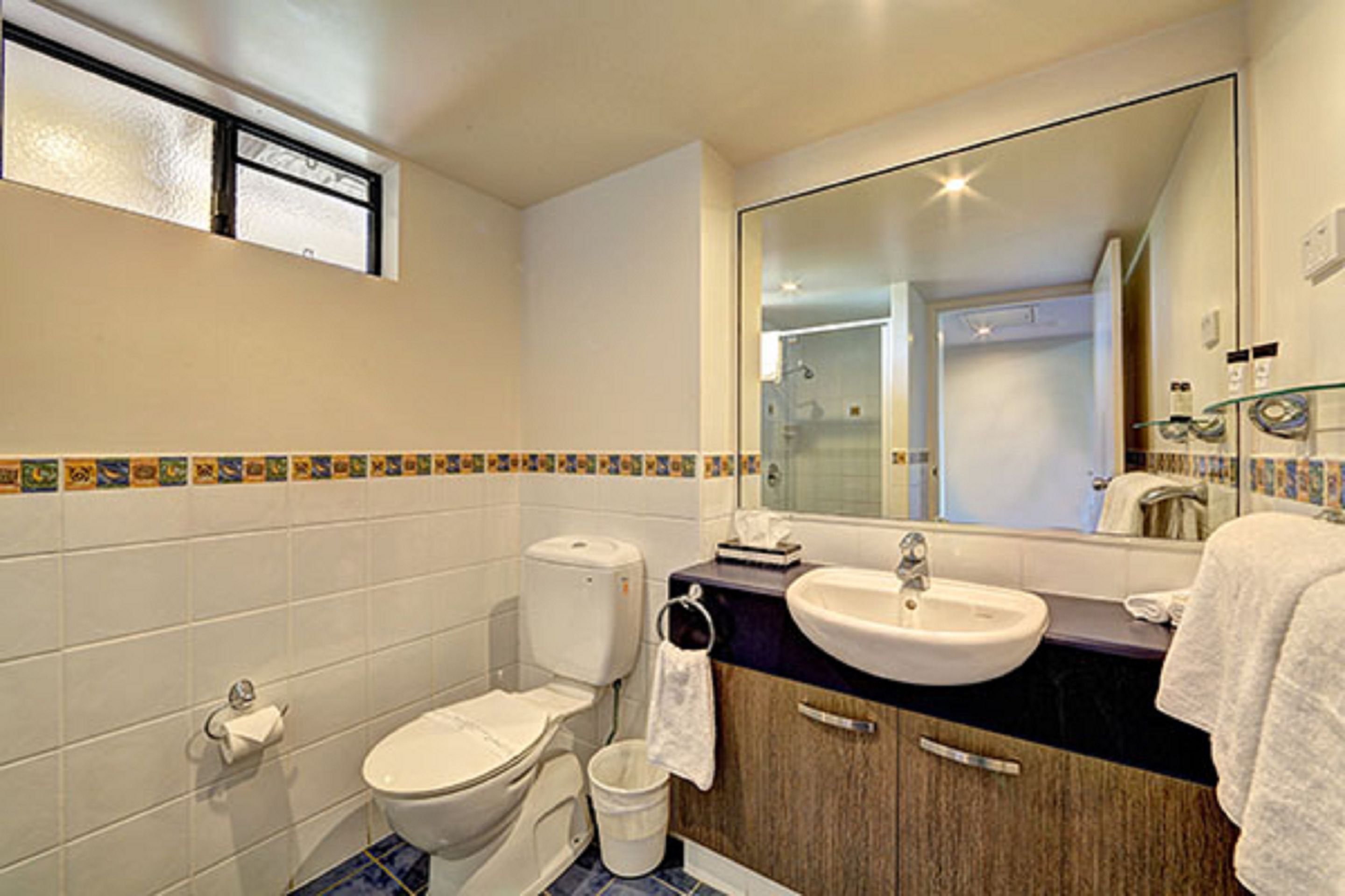 Een badkamer met toilet, wastafel en spiegel.