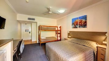 A room with bunk beds, a desk, a chair, a bed with a headboard, a nightstand, a wall-mounted TV, and two paintings.
