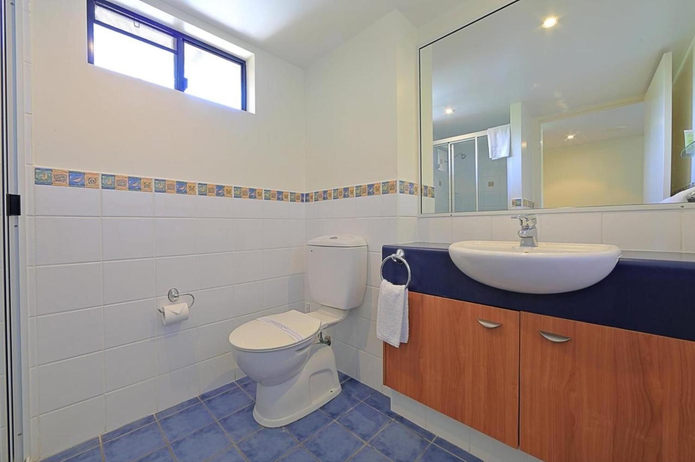 A bathroom with a toilet, sink, and mirror.