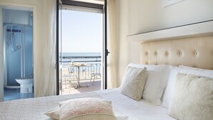 A hotel room with a large bed, a view of the sea, and a balcony with outdoor seating. - Strand (Bellaria-Igea Marina)