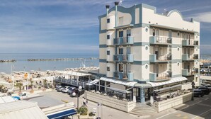 A multi-story hotel with balconies, a beach view, and a restaurant area with outdoor seating. - Strand (Bellaria-Igea Marina)