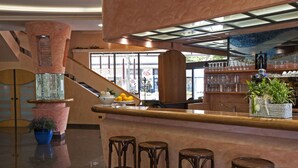 A bar area with stools, a counter, and a potted plant. - Strand (Bellaria-Igea Marina)