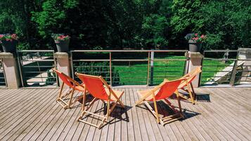 Une terrasse en bois avec deux chaises orange et des plantes en pot.