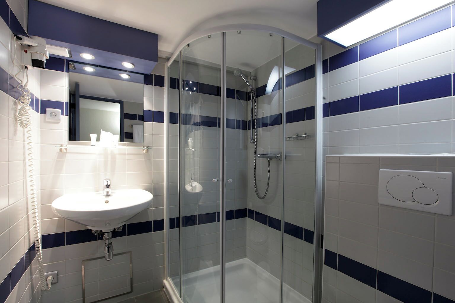 A bathroom with a glass-enclosed shower, a white sink, and a mirror.