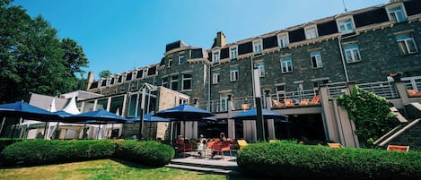 A courtyard with outdoor seating, stone building, and greenery.