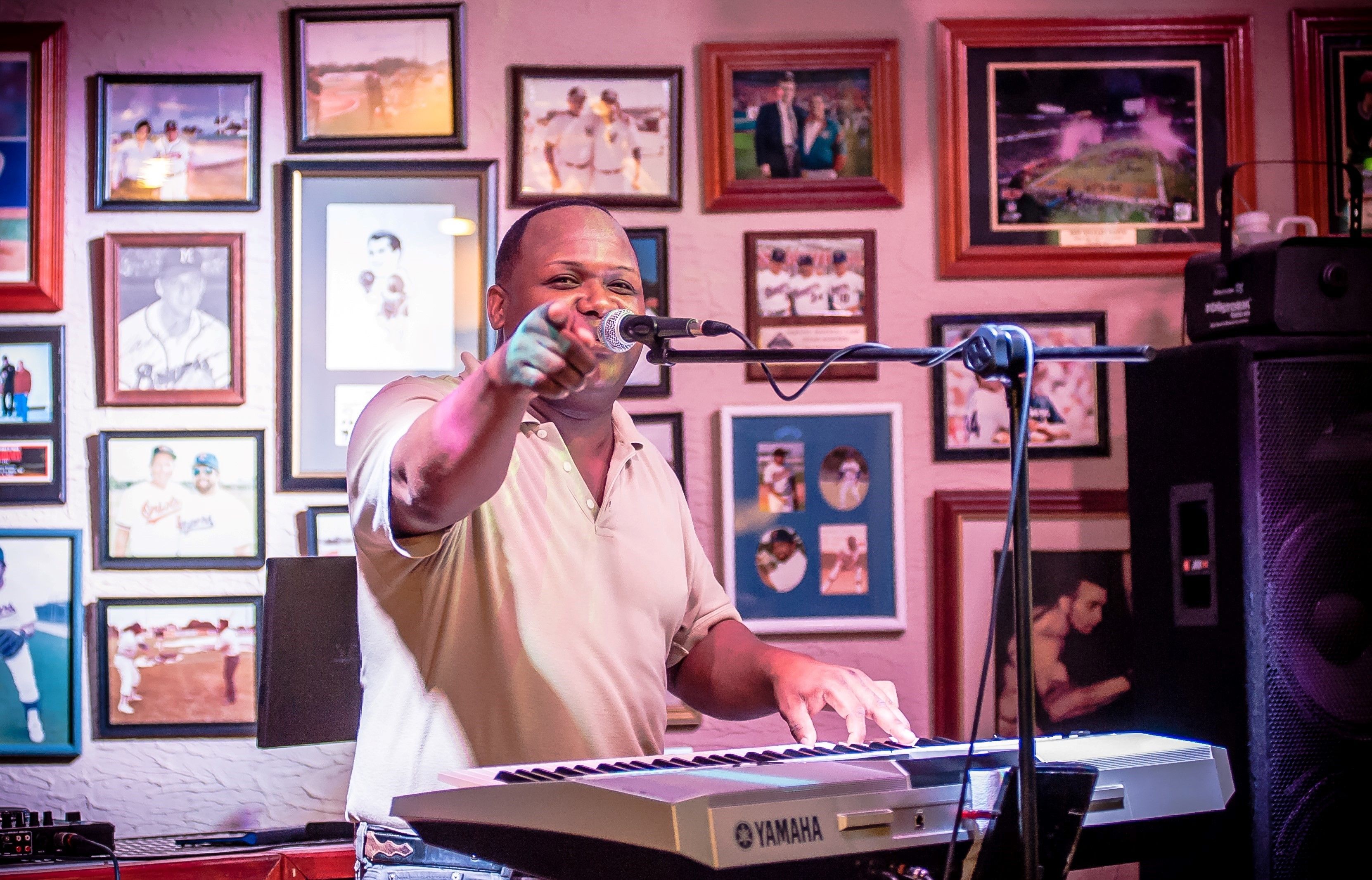 A person playing a keyboard in a room with framed pictures on the wall.