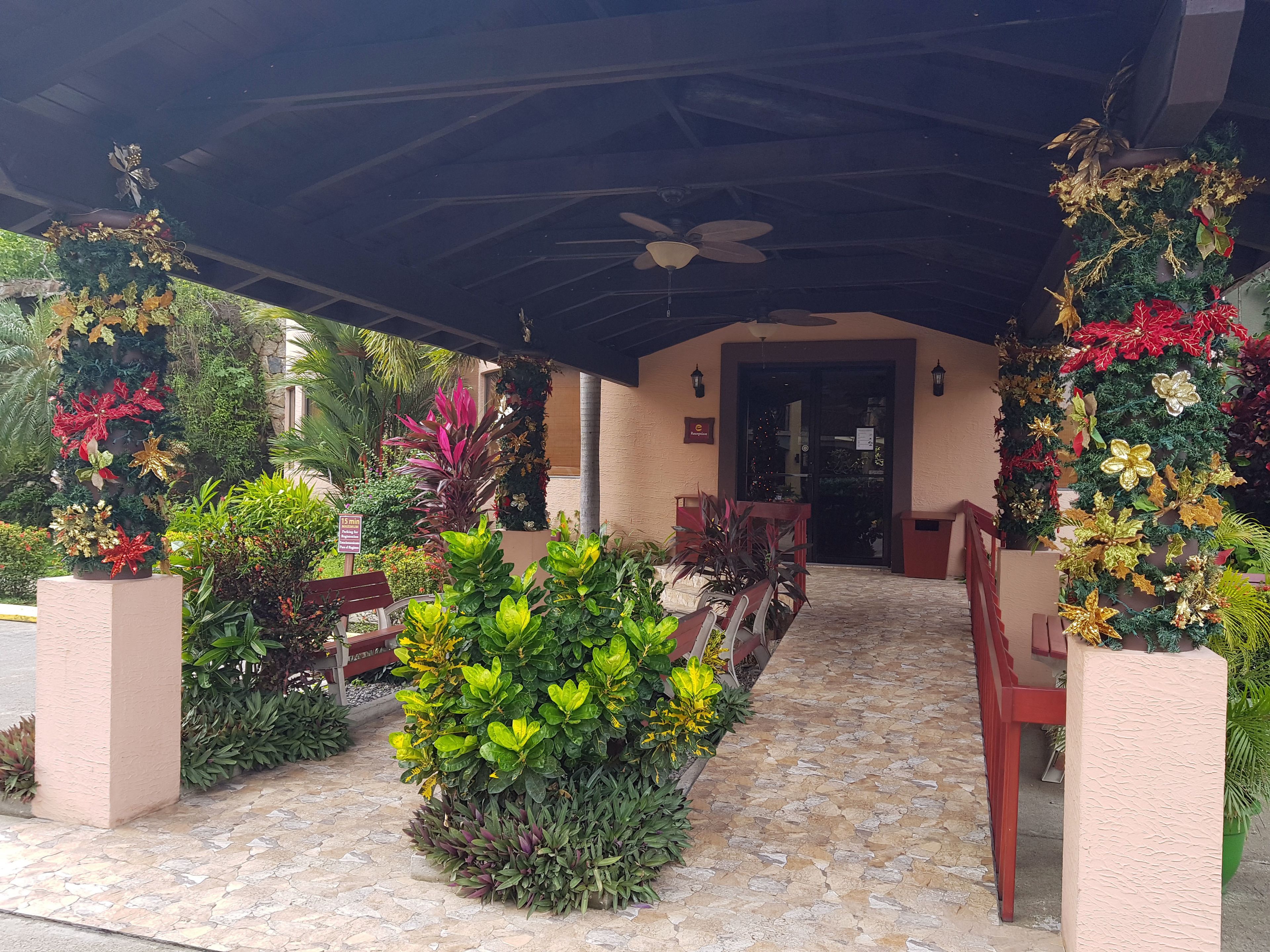 A covered outdoor area with a stone floor, benches, and potted plants.