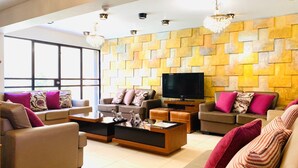 Una sala de estar moderna con un televisor grande, varios sofás y una pared con un diseño de piedra único.