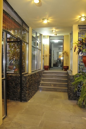 Una entrada de paredes de piedra con una escalera que lleva al segundo piso.