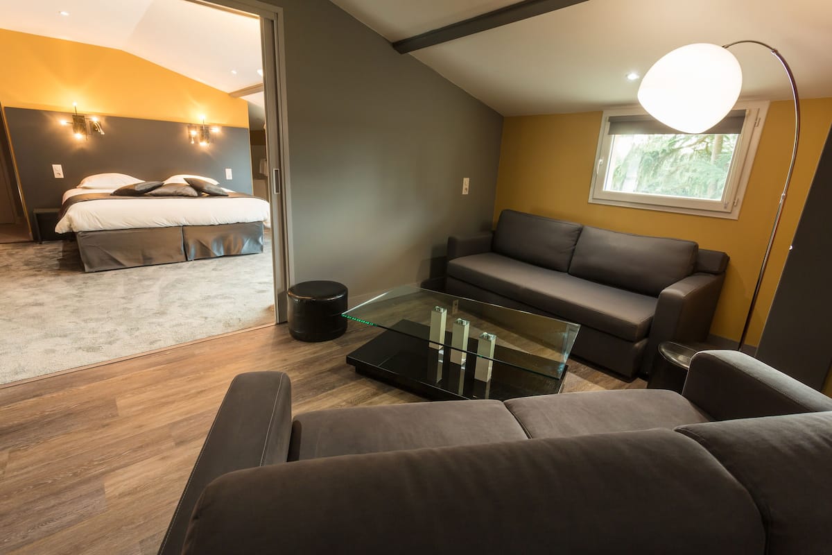 Ein modernes Schlafzimmer mit einem Bett, einem Glastisch, einer Couch und einer Lampe.