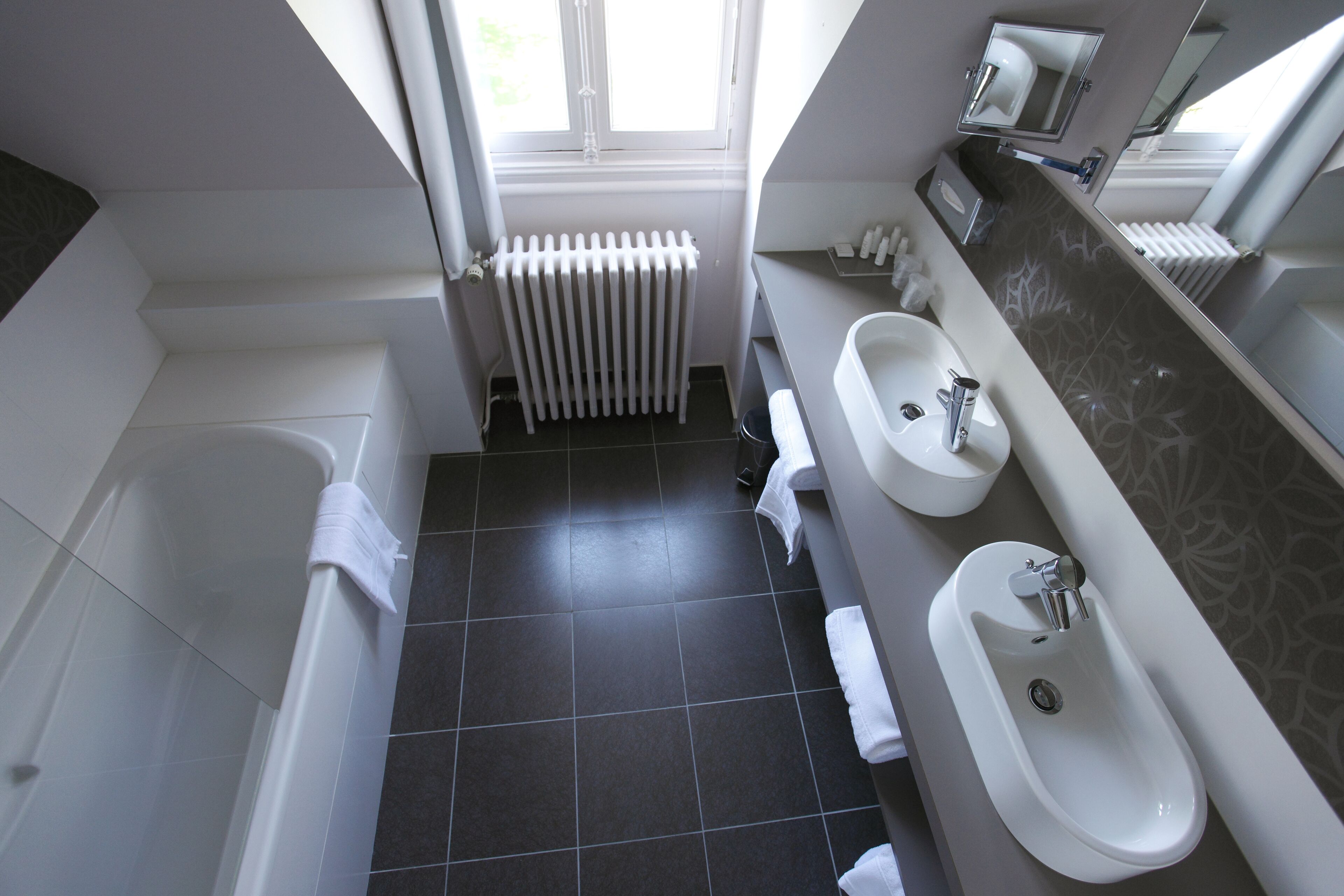 Un baño moderno con bañera, dos lavamanos y un ventanal que proporciona luz natural.