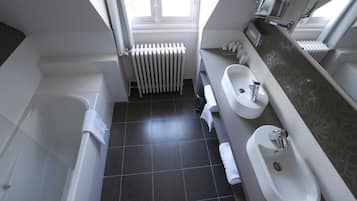 Un baño moderno con bañera, dos lavamanos y un ventanal que proporciona luz natural.