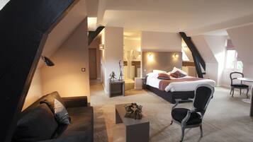 A modern loft bedroom with a large bed, a seating area with a coffee table, and a dining table.