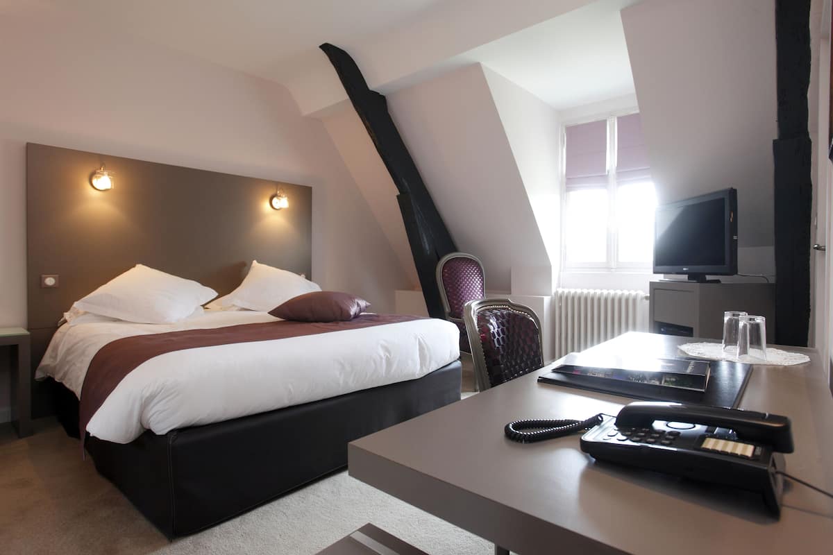 Ein Hotelzimmer mit Bett, Nachttisch, Schreibtisch, Stuhl und Fernseher.