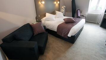 A bedroom with a bed, a black sofa, and a radiator.