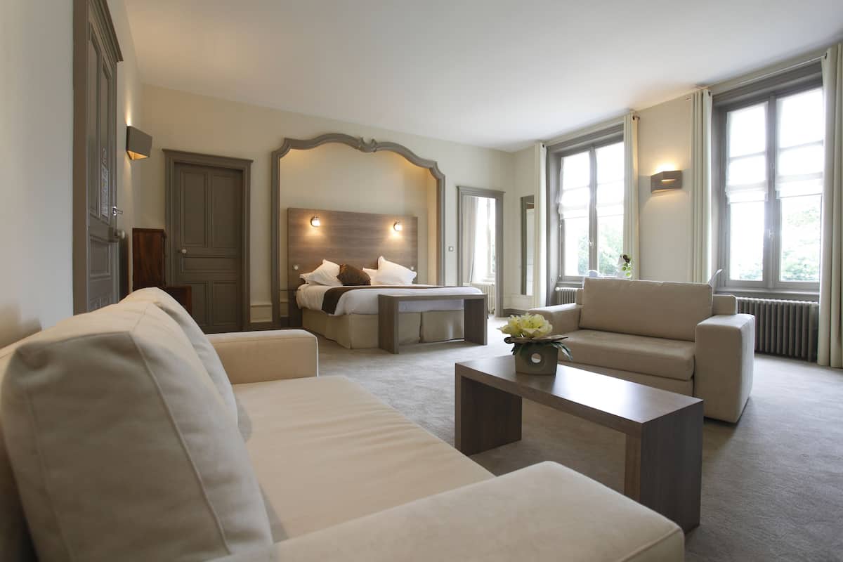 Ein Hotelzimmer mit einem Bett, zwei Sofas, einem Couchtisch und großen Fenstern.