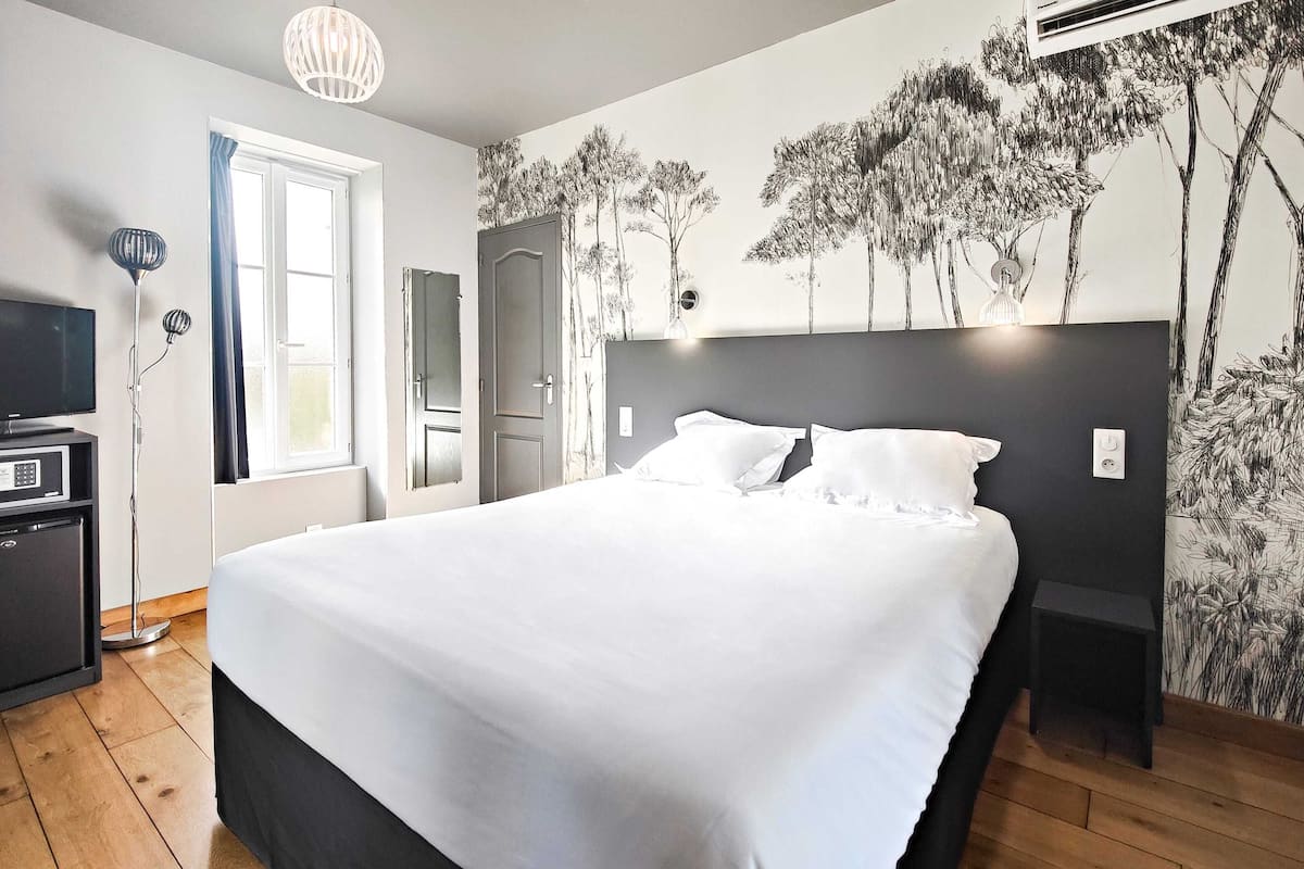 Ein Schlafzimmer mit einem großen Bett, einem Fernseher, einem Schreibtisch und einem Kleiderschrank.
