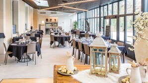 Um restaurante espaçoso com várias mesas preparadas para refeições, grandes janelas com vista e elementos decorativos como lanternas e um cobertor de pele.