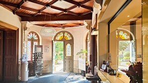 Um hall de hotel com teto de madeira, janelas de vitrais e um balcão de recepção.