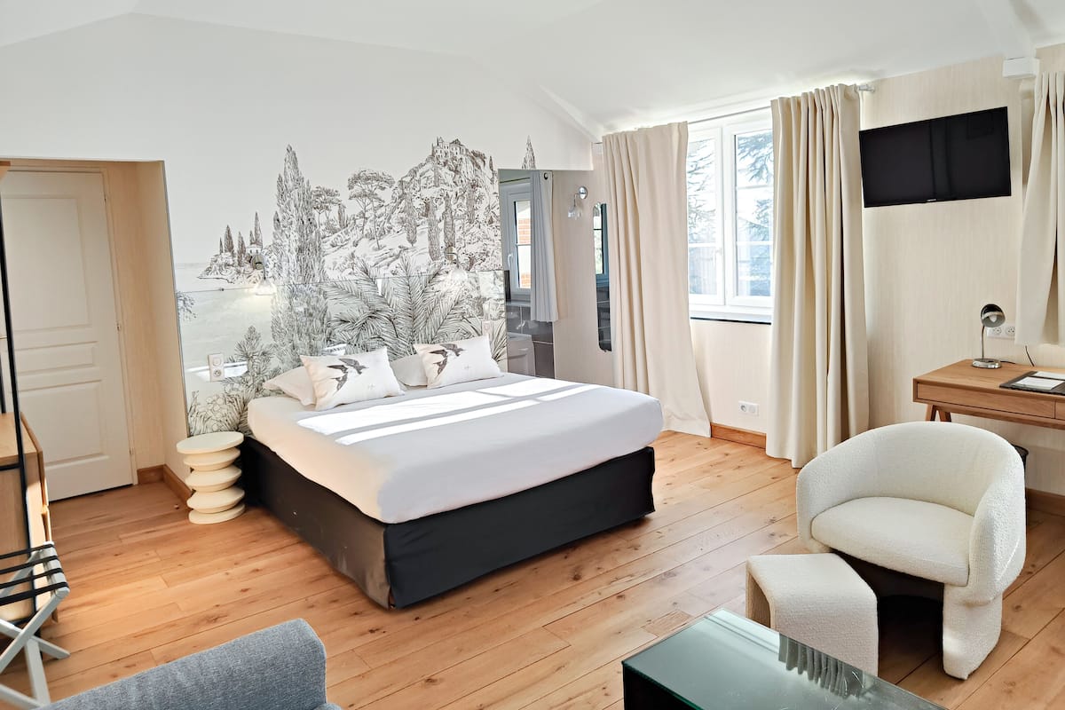 Ein modernes Schlafzimmer mit einem großen Bett, einem Schreibtisch, einem Stuhl und einem Fernseher.