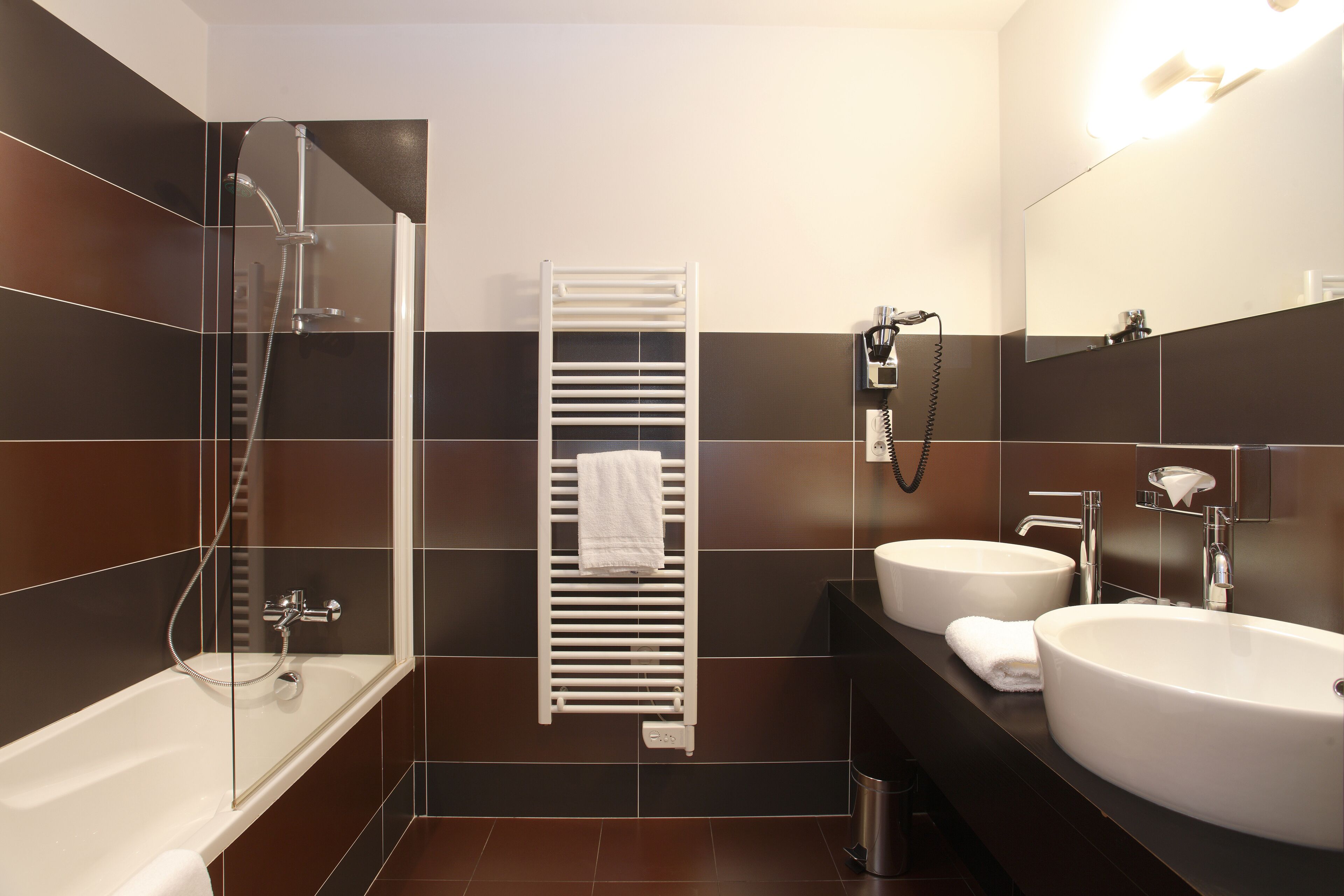 Un baño moderno con una bañera, dos lavamanos, un perchero y un espejo.