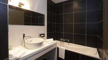 A modern bathroom with a white sink, mirror, and bathtub.