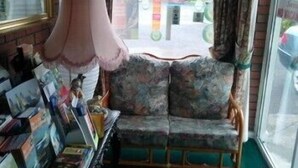 A room with a sofa, a small table with various items, and a window with a view of the outside. - The Branches (Galway)