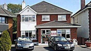 A two-story building with a sign 'B&B' indicating it is a bed and breakfast. There are two cars parked in front. - The Branches (Galway)
