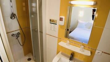 Un baño de hotel con ducha, lavabo y espejo.
