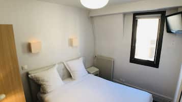 A bedroom with a bed, a nightstand, a wall-mounted TV, and a window.