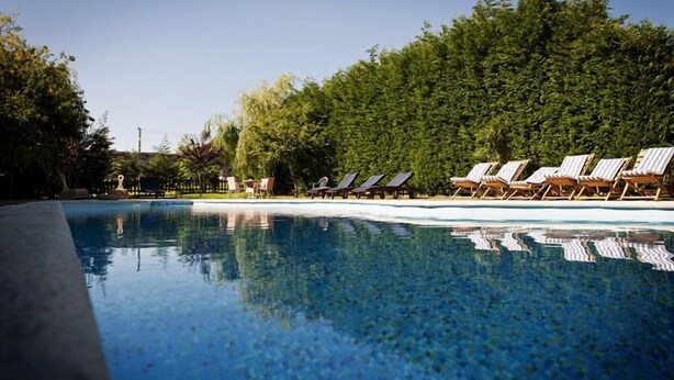 A clear swimming pool with lounge chairs and a dense hedge in the background. - Posada Santa Ana (Suances)