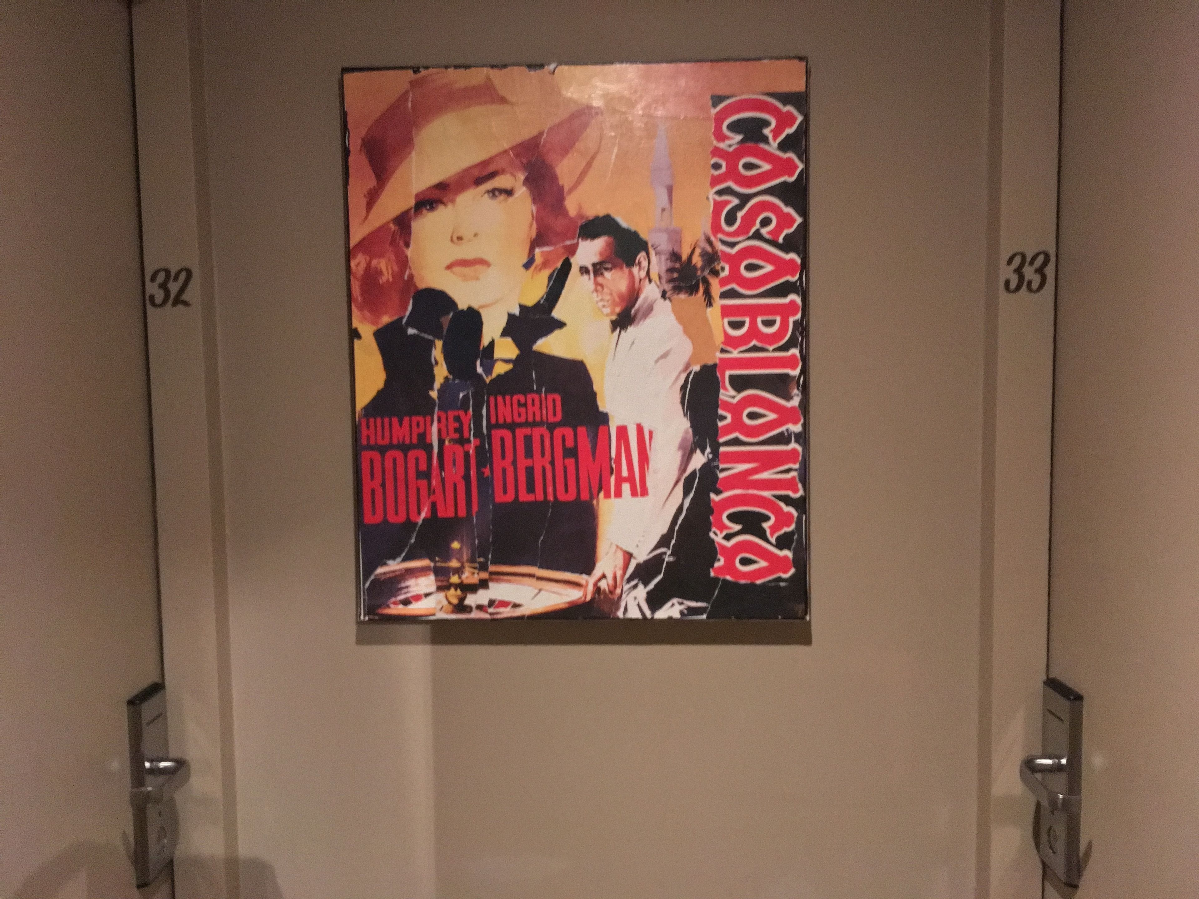 Póster de película enmarcado en una pared, con los números 32 y 33 visibles a cada lado.