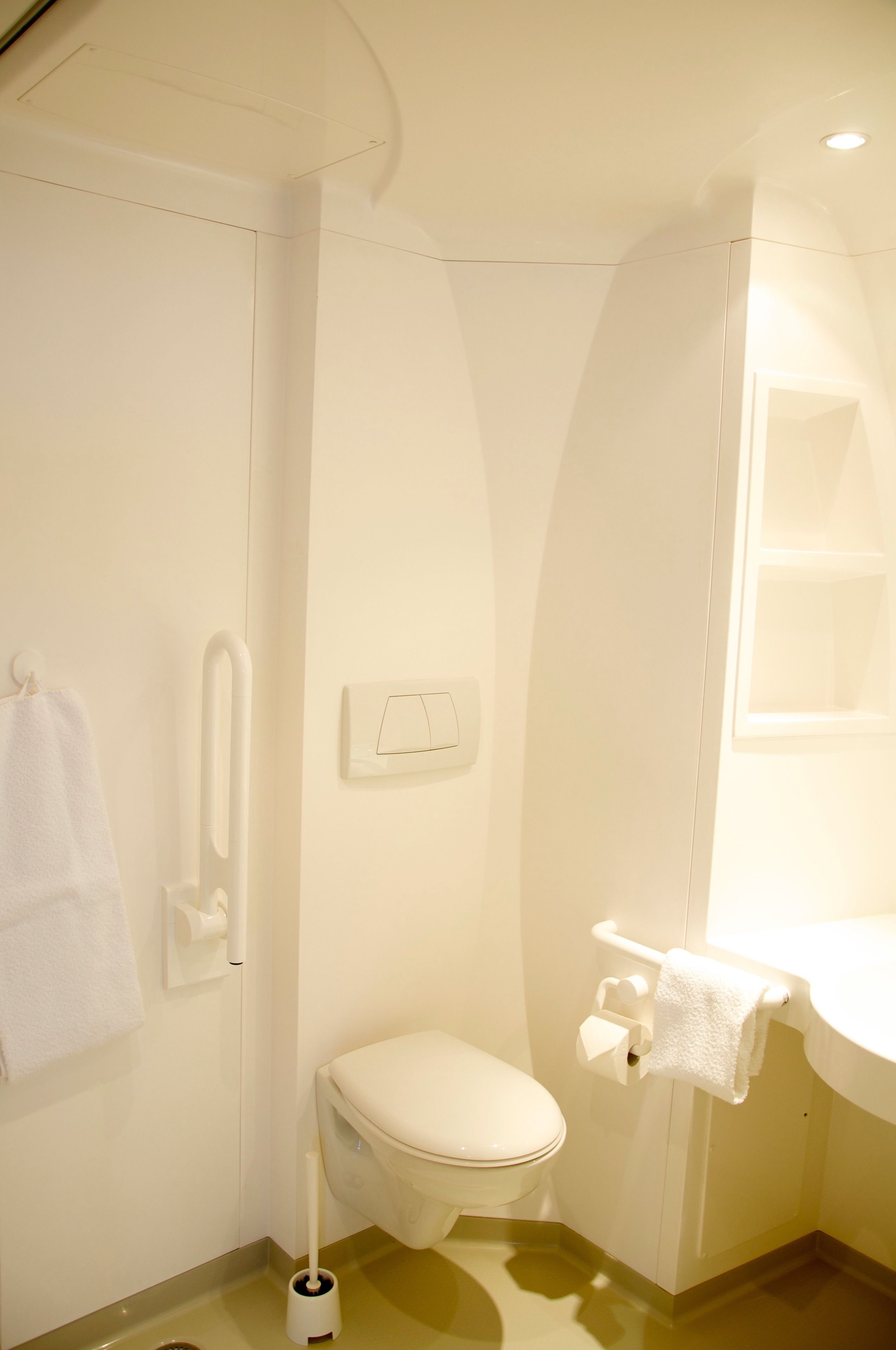 A small, clean bathroom with a toilet, a hand dryer, a towel rack, and a sink.
