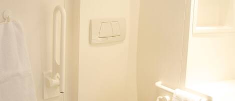 Un bagno piccolo e pulito, con un WC, un asciugamani ad aria, un portasciugamani e un lavandino.