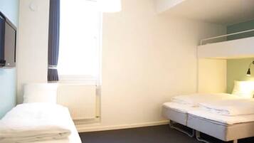 A hotel room with a bunk bed, a bedside table, a radiator, and a window with curtains.