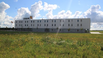 A motel with a flat roof, multiple windows, and a sign indicating its name.