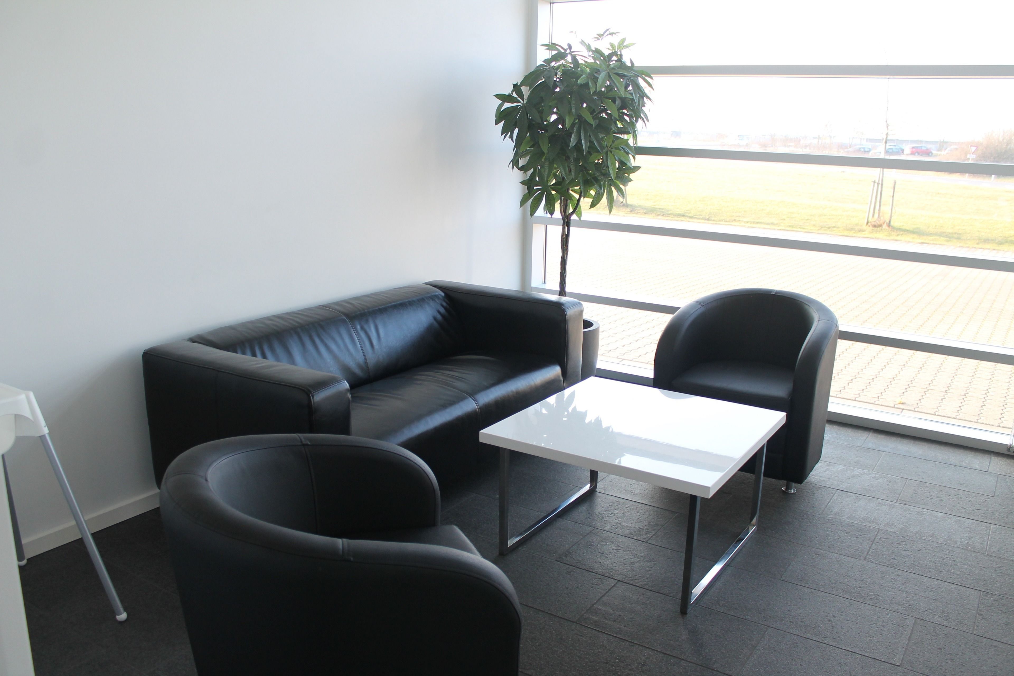 A modern office space with a black leather couch, a white table, and a black chair.