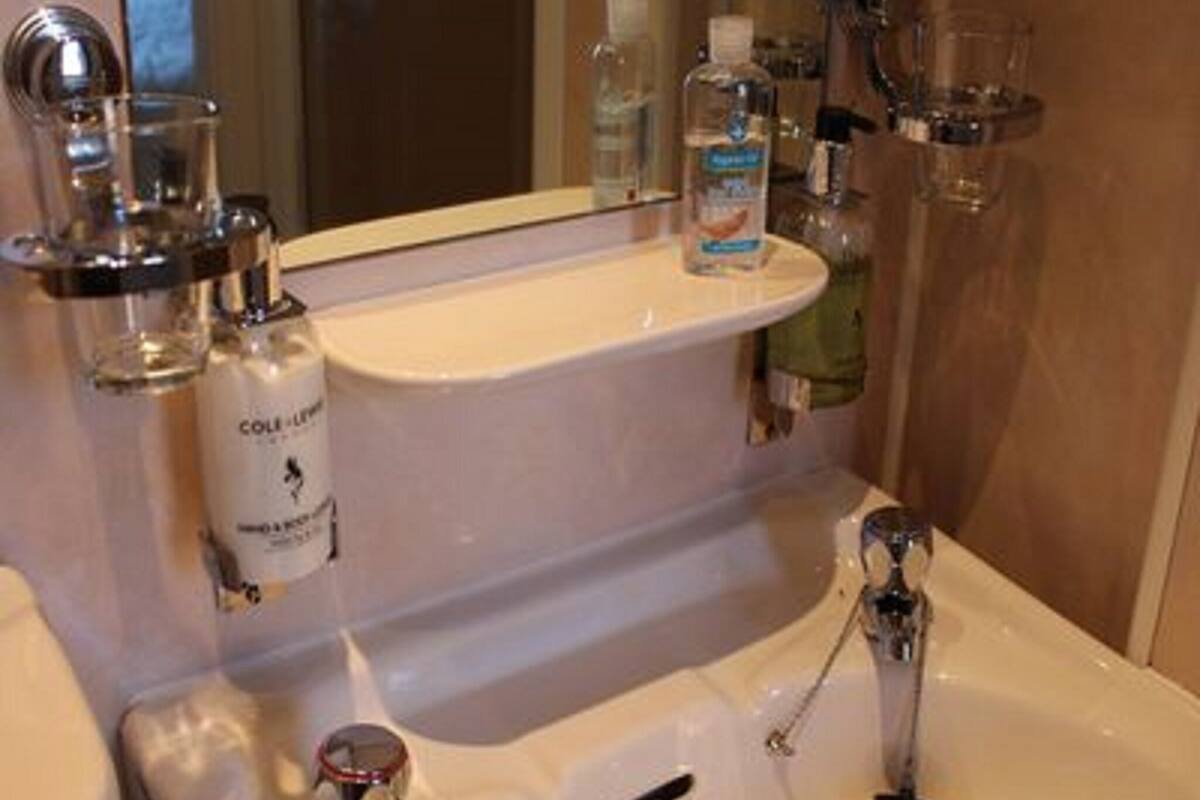 A bathroom with a white sink, a mirror, and a bottle of hand soap on the countertop.